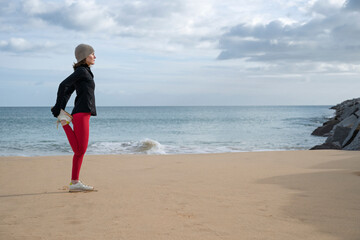 sporty woman doing a leg stretching warm up exercise on the beach