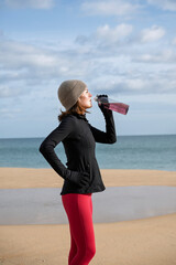 sporty woman runner drinking after jogging on the beach
