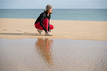 sporty woman tying her shoe preparing to run on the beach