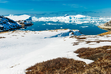 Floating icebergs create a stunning view in Ilulissat fjord of Greenland during bright daylight in a unique natural setting