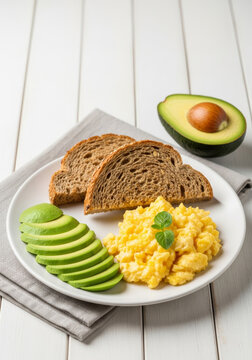 Healthy breakfast plate with scrambled eggs, whole grain toast and avocado slices