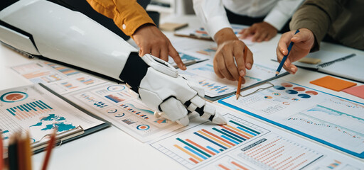 A collaborative scene in a modern office where human hands and a robotic arm analyze charts and statistics, showcasing the integration of technology in data analysis.Noogenesis
