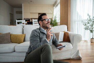 Fototapeta premium Happy man laughing while sitting on floor with notebook