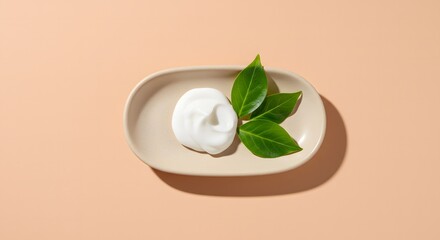 A delicate arrangement of creamy white lotion with fresh green leaves on a dish