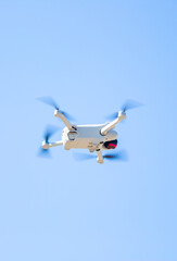 Quadcopter in flight against the sky. A small drone takes off above the ground.