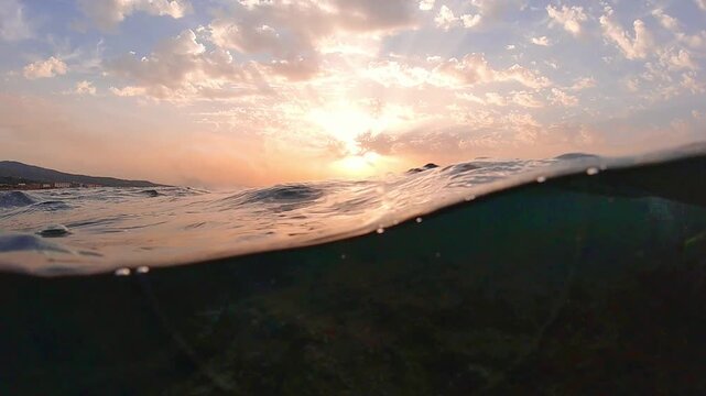 Underwater part and sunset skylight splitted by waterline, underwater bubbles. Beautiful clouds and bright sun over sea water, Real image very suitable for backgrounds in Mediterranean sea, undersea.