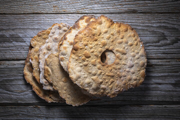 Top-down view of round sourdough crispbread stacked on rustic aged wooden table, homemade Scandinavian kn&auml;ckebrot, high contrast, appetizing baked goods