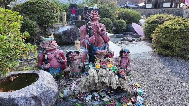 Japanese Oni Statues Surrounded by Colorful Amulets in Temple Garden