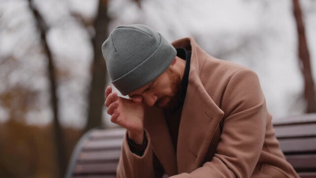 Upset Man Crying and Rubbing His Eyes While Contemplating Outdoors
