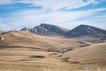 Fototapeta premium Wide mountain landscape of rolling golden hills and distant mountains in Bucegi National Park, Romania