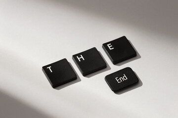 Black keyboard keys spelling "THE End" on gray background with soft shadow, symbolizing conclusion or finale.