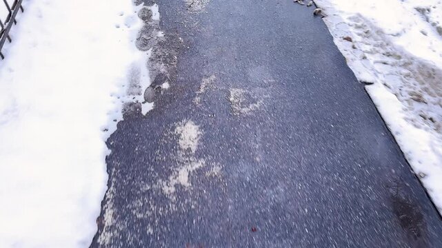 Deicing chemicals on pavement in winter. Salt grains on icy sidewalk, paving slab with rock salt in cold season. Slippery road sprinkled with technical salt and calcium. Prevent slipping concept