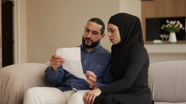 Arab couple reading bad news letter, upset about immigration refusal notice