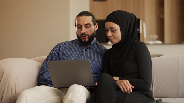 Muslim couple choosing hotel for vacation on laptop, online travel planning
