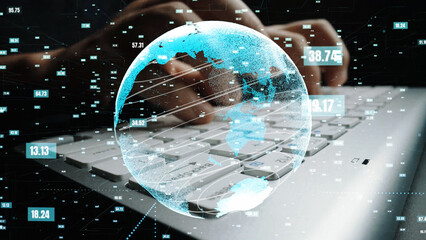 Hands typing on a laptop keyboard with a glowing globe overlay representing global connectivity and data analysis in a digital workspace, showcasing modern technology. Xenic