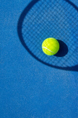 A tennis ball and racket silhouette on a blue outdoor court.