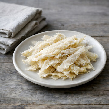 Ultra-realistic food photo of traditional Icelandic har&eth;fiskur on a simple ceramic plate with natural linen on a wooden surface. Nordic rustic minimal style, soft daylight, cool tones.