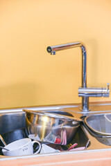 Dirty dishes in a stainless steel kitchen sink under a modern faucet. Daily household chores, messy kitchens, cleaning routines, home life, and a realistic concept of home lifestyle.