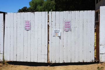 Old white wooden double gate with DO NOT BLOCK DRIVEWAY signs