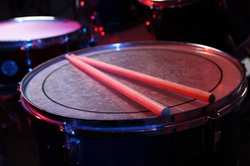 Obraz premium Wooden drumsticks on drum in color light, closeup