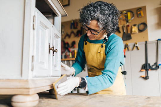 Woman restoring vintage furniture in workshop