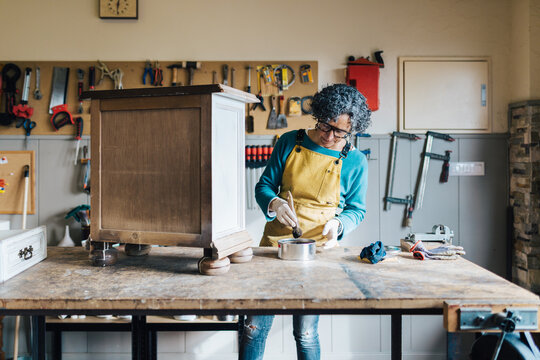 Woman restoring furniture in a workshop setting