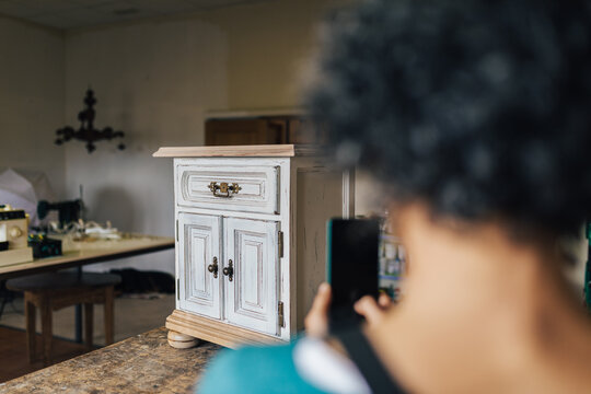 Woman photographing restored furniture in workshop