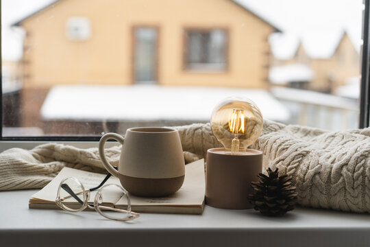 Cozy winter scene with mug, book, and glowing bulb