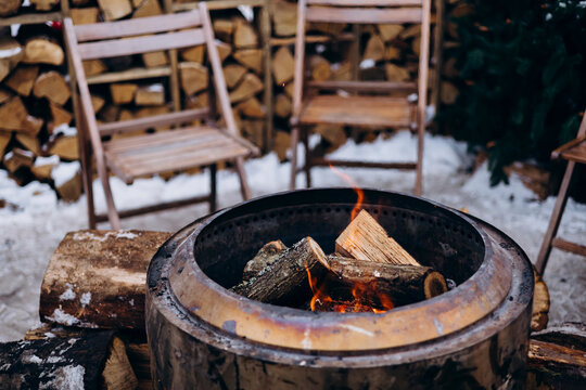 Outdoor fire pit with chairs in snowy setting