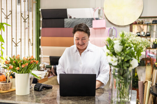 Small business owner managing flower shop with laptop