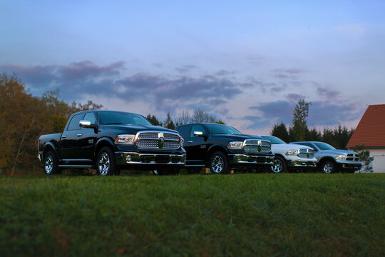 Mitrov, Czech Republic - October 18 2014: Row of Dodge Ram 1500 pickup trucks parked on a green field at sunset. American heavy duty utility vehicles.
