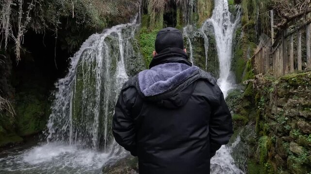 Tilt up de hombre observando la majestuosa cascada en Tobera