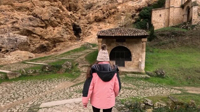 Mujer acerc&aacute;ndose al humilladero del Santo Cristo desde el puente medieval en Tobera