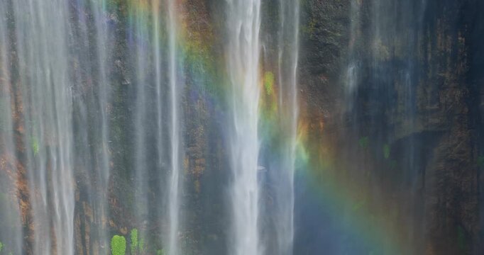 Close-Up Detail of Tumpak Sewu Waterfall with Rainbow Over Mossy Cliff, Indonesia