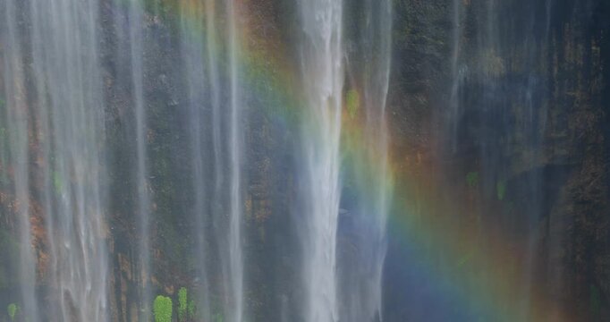 Close-Up Detail of Tumpak Sewu Waterfall with Rainbow Over Mossy Cliff, Indonesia
