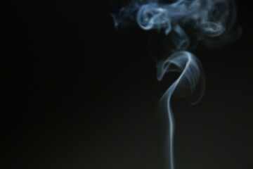 Obraz premium Blue smooth texture smoke from incense aroma stick in motion rising above in holiday celebration with empty copy space dark background. Yoga calm meditation, relaxation concept 