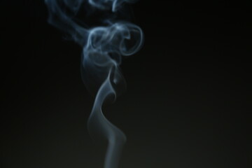 Blue smooth texture smoke from incense aroma stick in motion rising above in holiday celebration with empty copy space dark background. Yoga calm meditation, relaxation concept	
