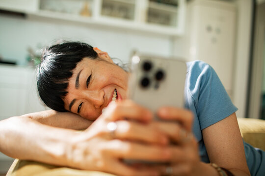 Smiling woman using smartphone on couch at home