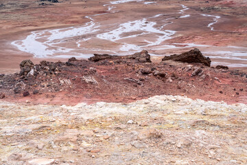 Rocks and water on the red earth at the Gunnuhver geothermal area on the Reykjanes Peninsula during a day in March