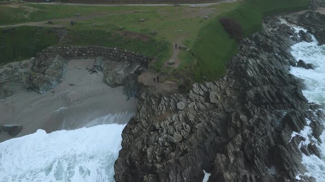 drone shot of tourists looking out from headland North Fistral beach at cornwall cliffs at newguay