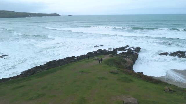 drone shot of tourists looking out from headland North Fistral beach cornwall cliffs at newguay 