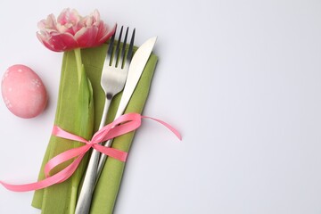 Easter table setting. Beautiful silverware with tulip and painted egg on white background, top...
