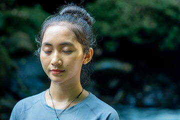 Asian woman doing yoga alone in nature. Maintaining a healthy body and mind.