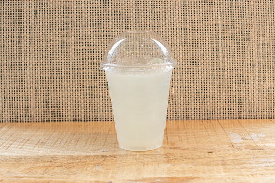 The promise of sweet and tangy relief on a hot day, materialized in a glass of lemonade with an undissolved sugar cube at the bottom and a lemon peel curled around the rim.