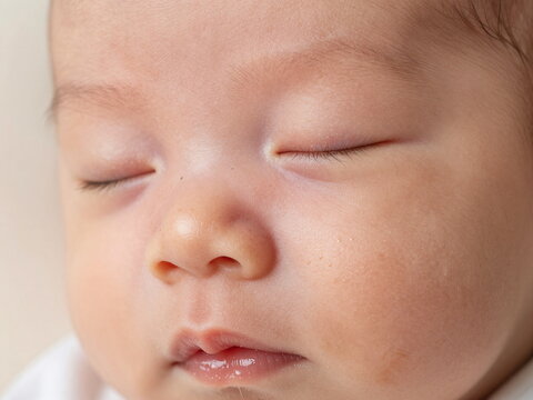 Macro Close Up of Sleeping Newborn Face Showing Natural Milia Milk Spots and Peach Fuzz on Nose.