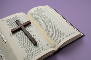 Wooden cross on an open Bible. Christian concept. Lent, symbolizes penance, sacrifice, and mourning.
