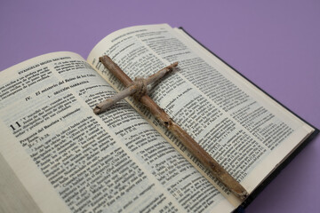 Natural wood cross on an open Bible. Christian concept. Lent, symbolizes penance, sacrifice, and mourning.