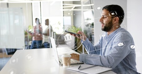 Working man in business-casual shirt using smartphone and laptop at office with HUD, copy space