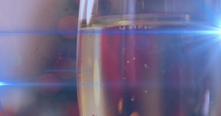 Showing tall narrow champagne flute sparkling in dim bar, with rising bubbles and blue lens flares