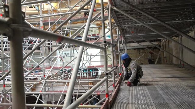 Construction workers working intensively on scaffolding structure.